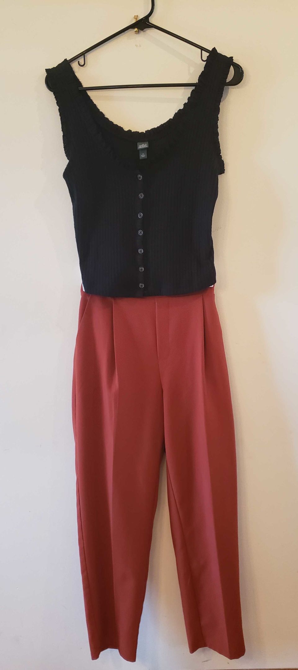 A tank top and pants outfit hangs on a hanger